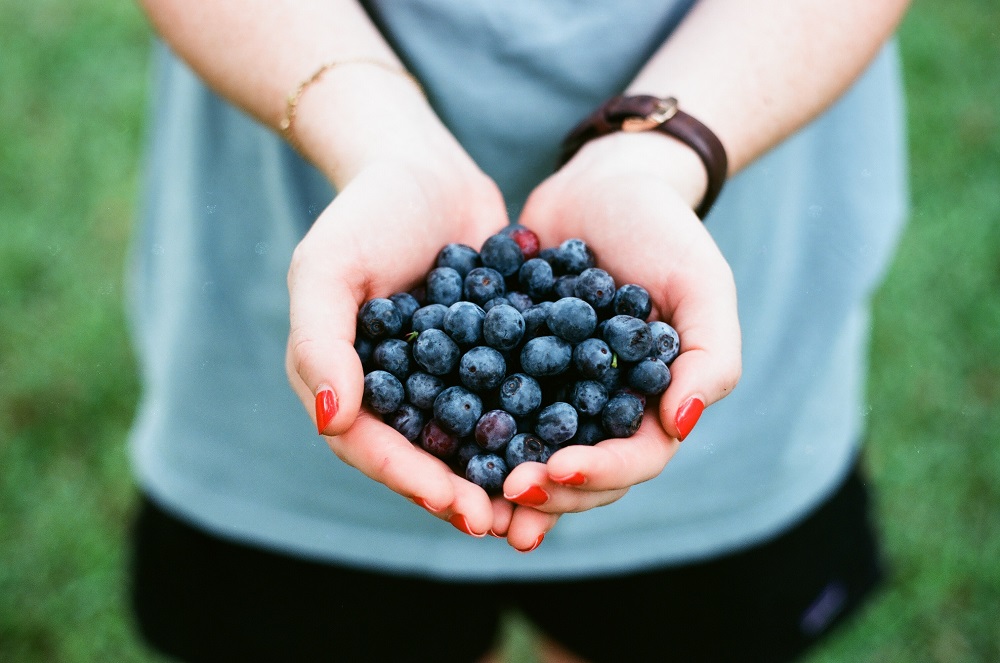 Woman with haldful of berries signifying our relationship with food